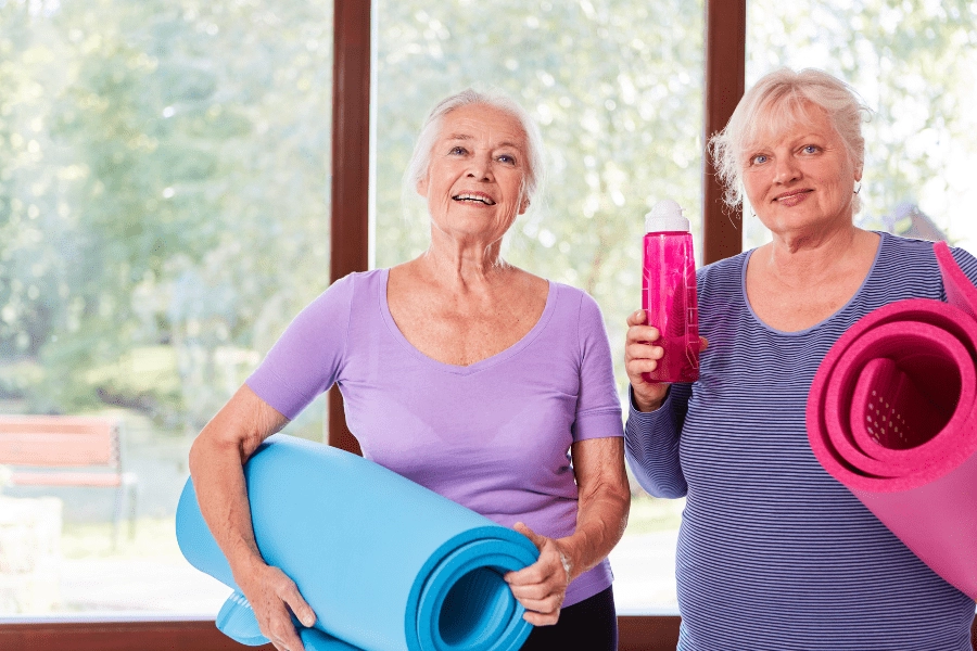 Senior friends carrying yoga mats.