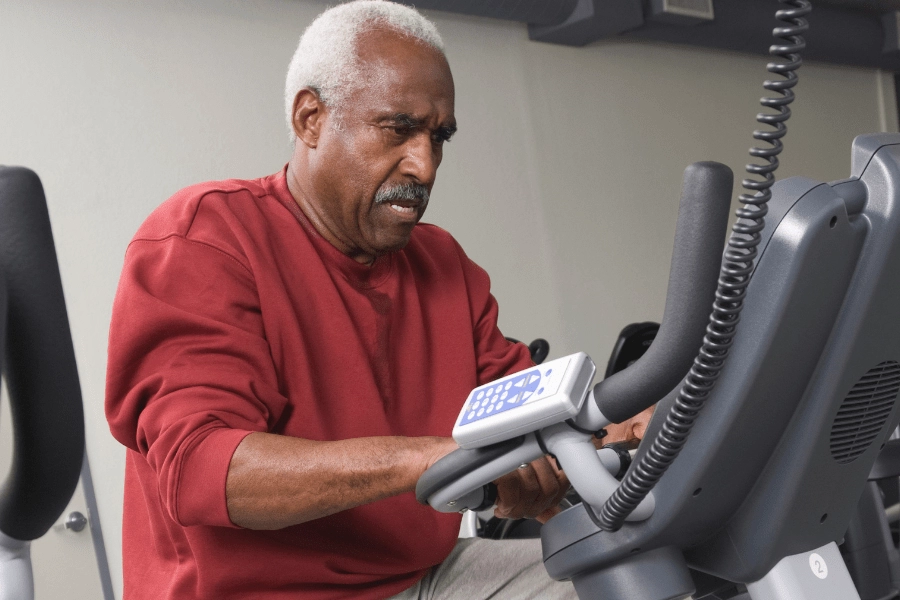 Senior man using a stationary bike as one type of indoor exercises for seniors.