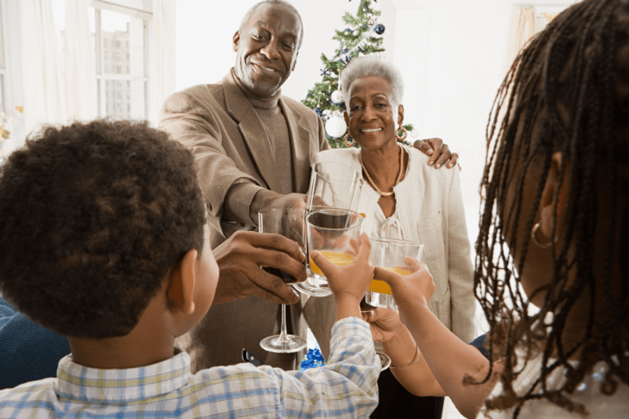 Summer activities for seniors - Grandparents toasting glasses of juice with their two grandchildren. - MeetCaregivers