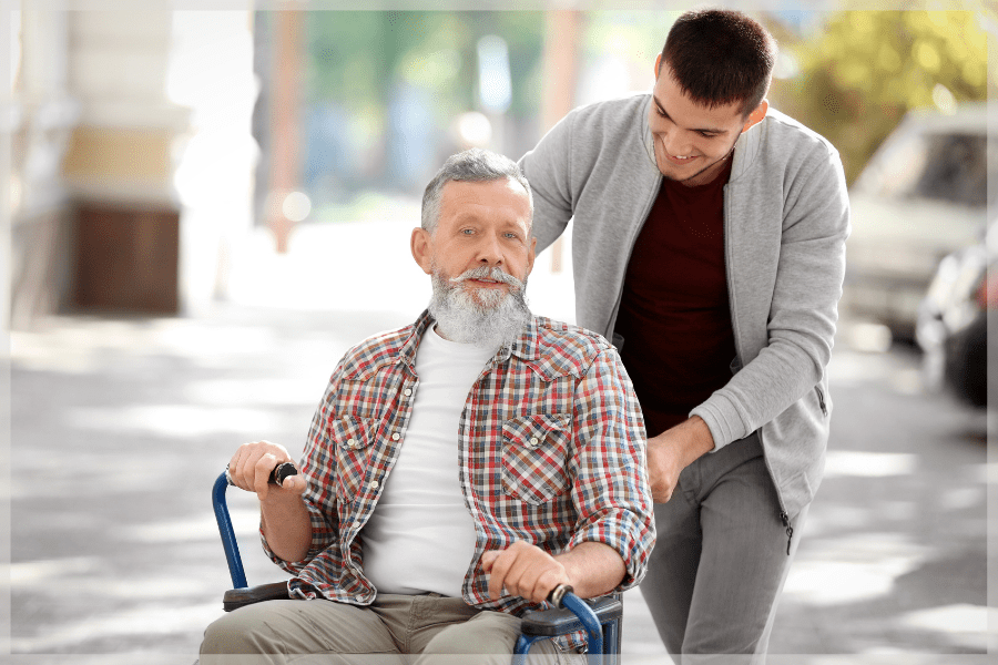 Sandwich generation - Adult son assisting his father in a wheelchair - MeetCaregivers
