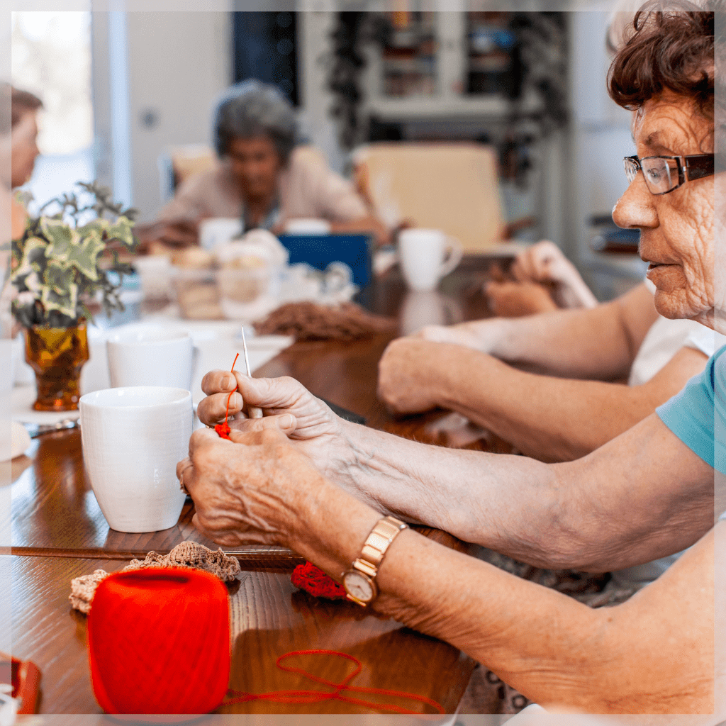 Elderly woman crocheting with a group of seniors at one of several adult day programs - MeetCaregivers