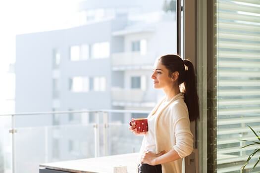 Respite Care - Woman Leaning Against Window With Mug