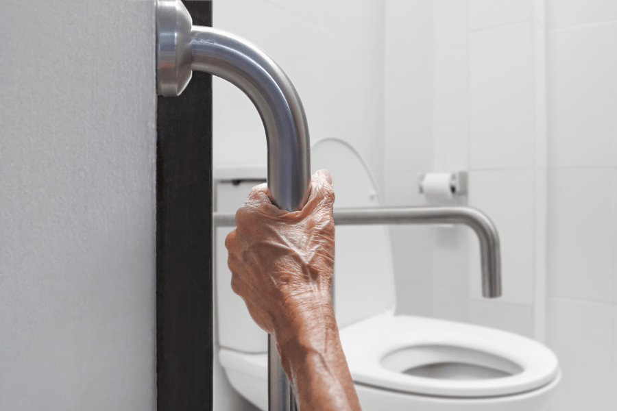 Aging in place remodeling - Elderly person holding a bathroom grab bar - MeetCaregivers