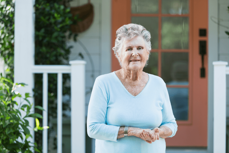 Aging in place remodeling - Smiling elderly woman standing in front of her home - MeetCaregivers