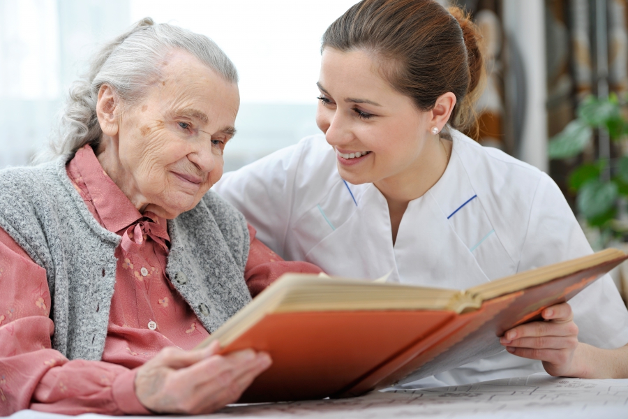 Dementia Care - A Caregiver Reading To A Senior