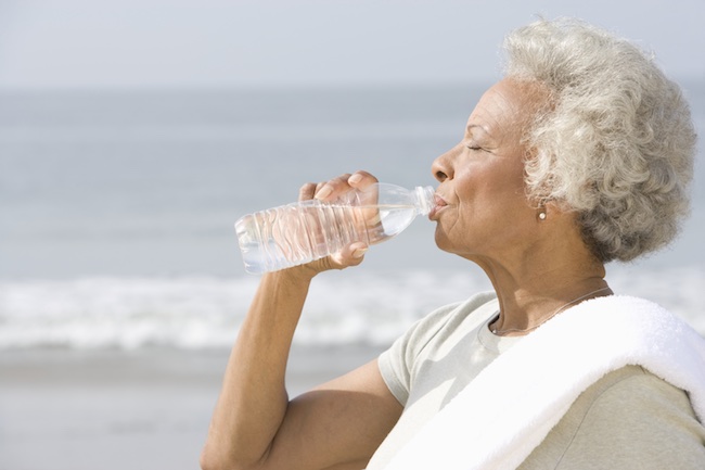 Senior Woman Drinking Water From Bottle At Beach