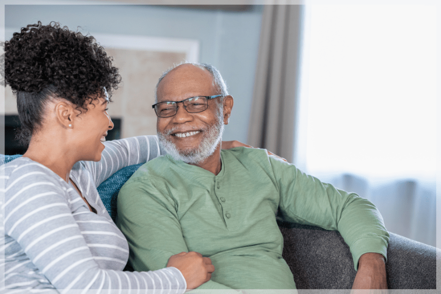 National Family Caregivers Month - Granddaughter laughing on the couch with her grandfather - MeetCaregivers