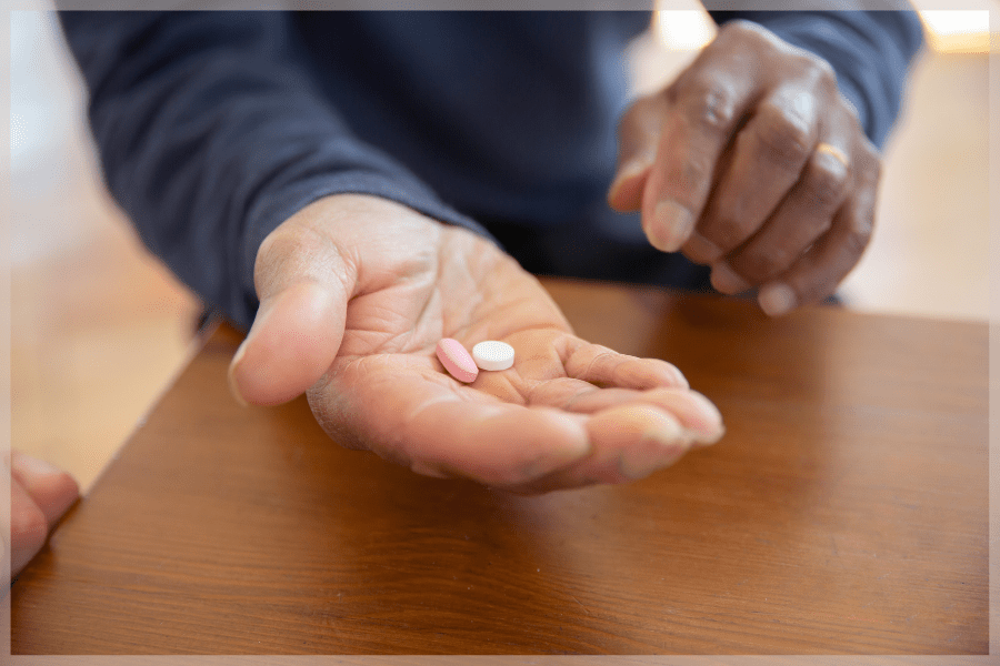 Appetite Loss In Elderly Adults Person holding a pink pill and white pill in the palm of their hand MeetCaregivers