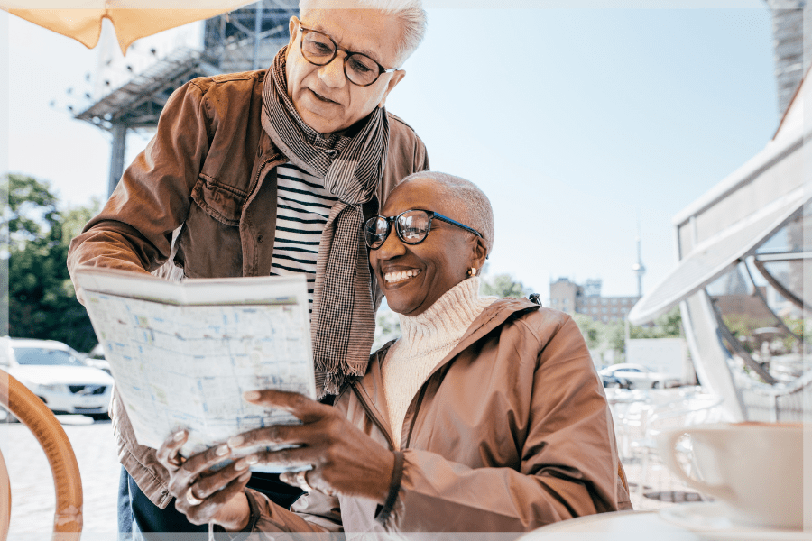 Travel tips for seniors - Older couple pointing at map while traveling - MeetCaregivers