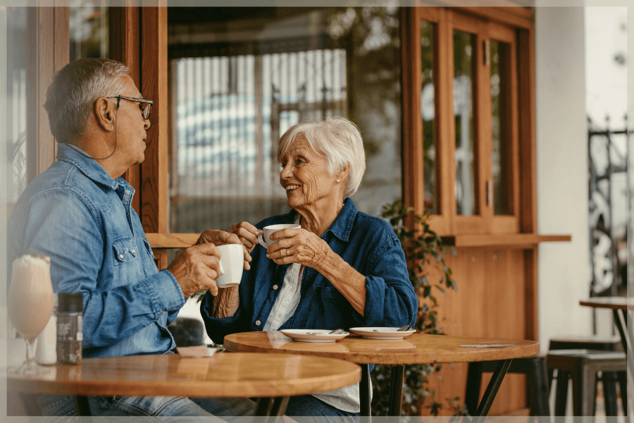 Senior dating - Older man and woman drinking coffee and talking in an open air cafe - MeetCaregivers