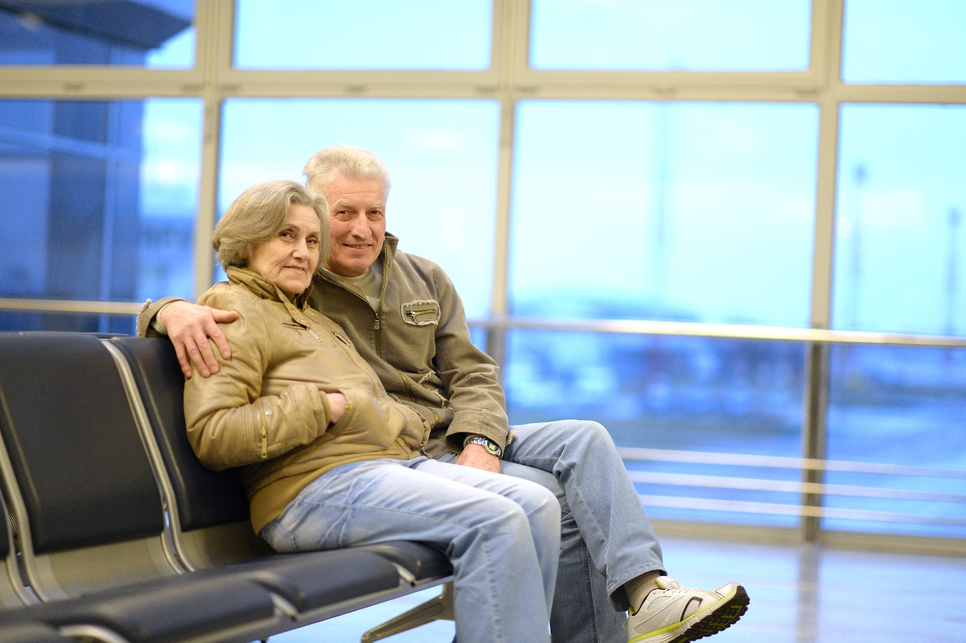 Senior Travel - Senior Couple Sitting At Their Gate In The Airport