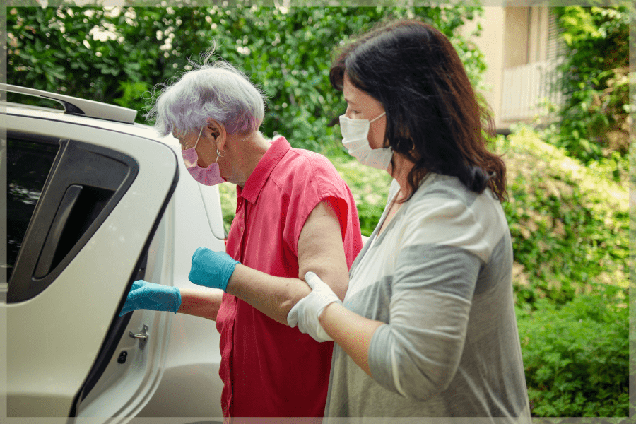 Coronavirus tips for older adults - Caregiver helping elderly woman into a car - MeetCaregivers