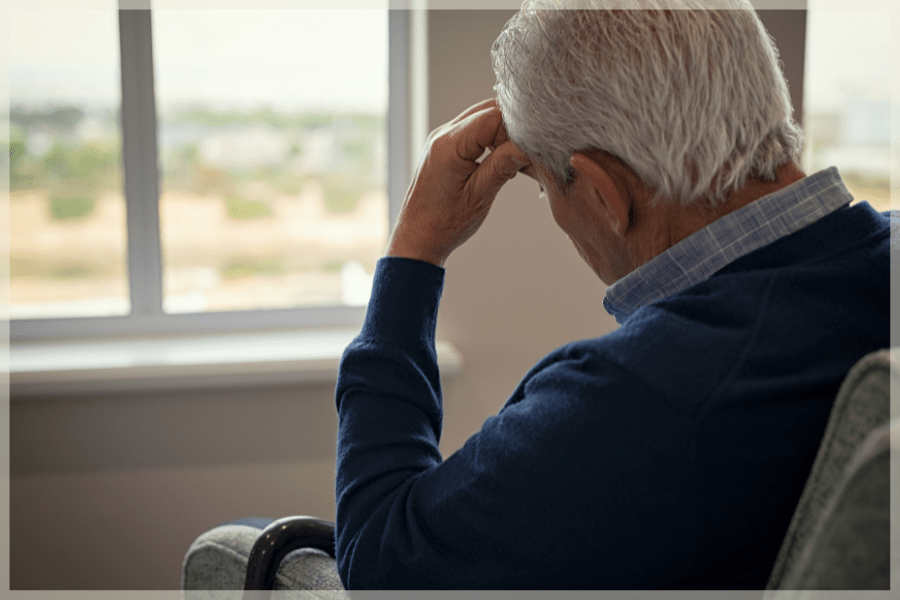 Elder abuse - Stressed senior aged man sitting in an armchair facing the window - MeetCaregivers