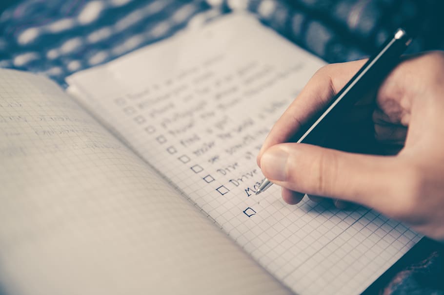 person-writing-bucket-list-on-book