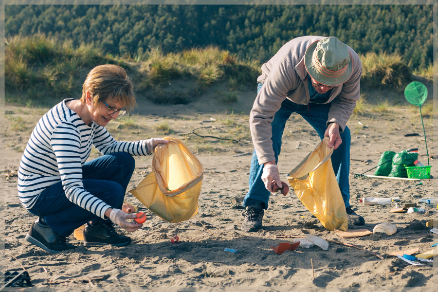 Two seniors picking up trash on the beach for National Volunteer Week
