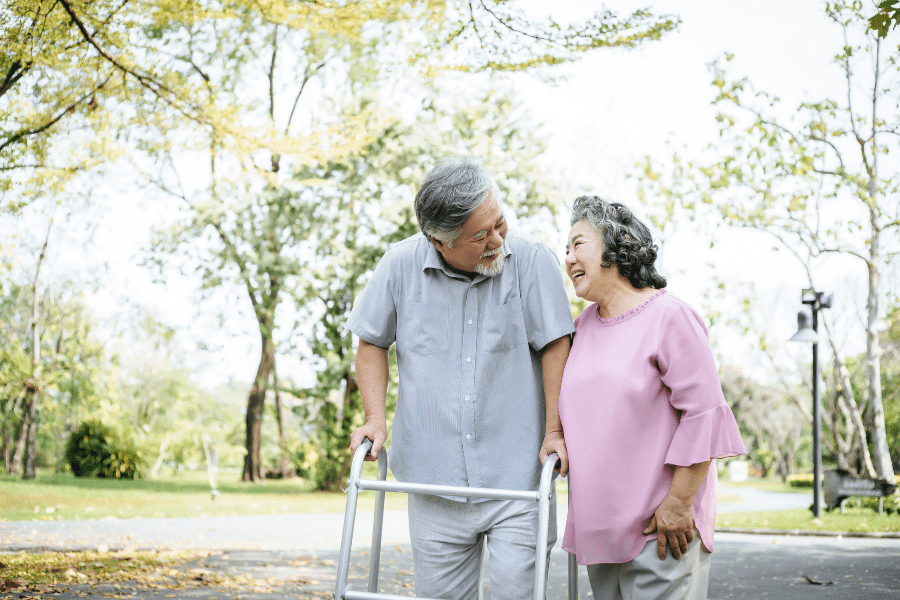 Men's Health Month – Woman Assisting Her Senior Husband Who's Using A Walker For Support