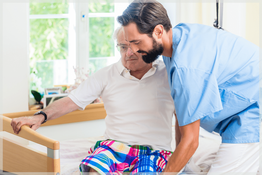 Benefits of home care - Caregiver helping elderly man sit up in bed - MeetCaregivers
