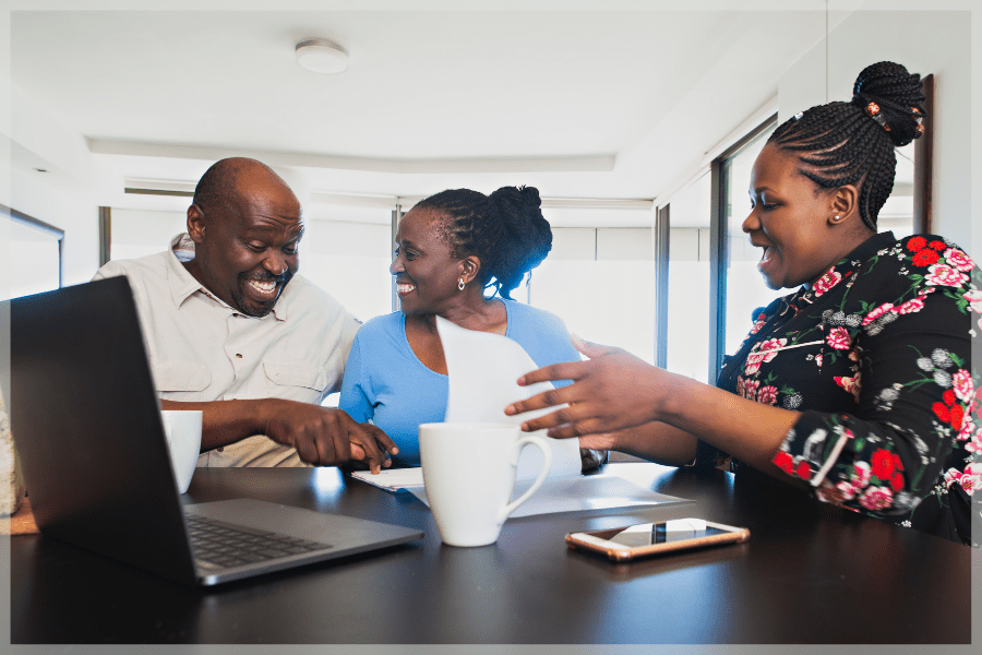 Benefits of home care - Senior couple celebrating while consultant flips through paperwork - MeetCaregivers