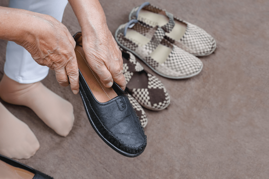 Elderly woman putting on shoes without daily living aids