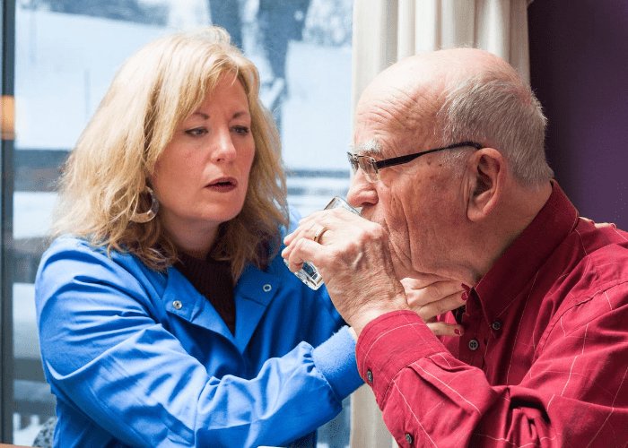 woman-testing-senior-man's-swallowing-function-while-drinking-water
