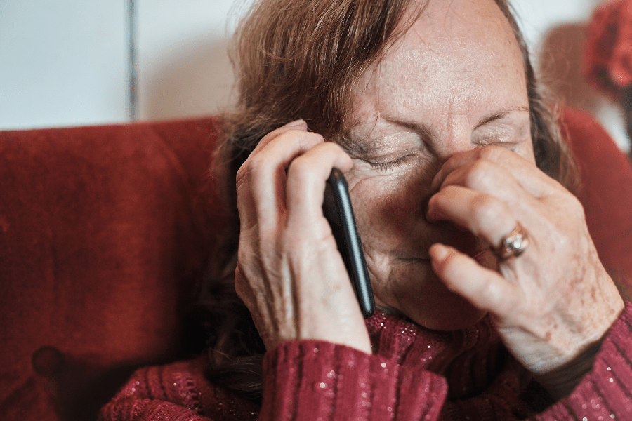 Upset senior woman holding smartphone hearing bad news