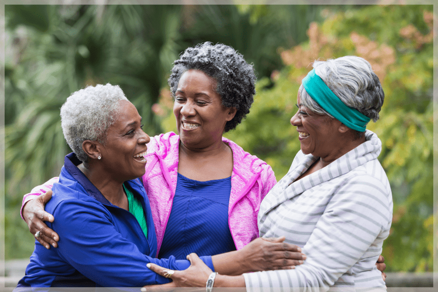 Healthy Aging Month Three senior friends hugging outside MeetCaregivers