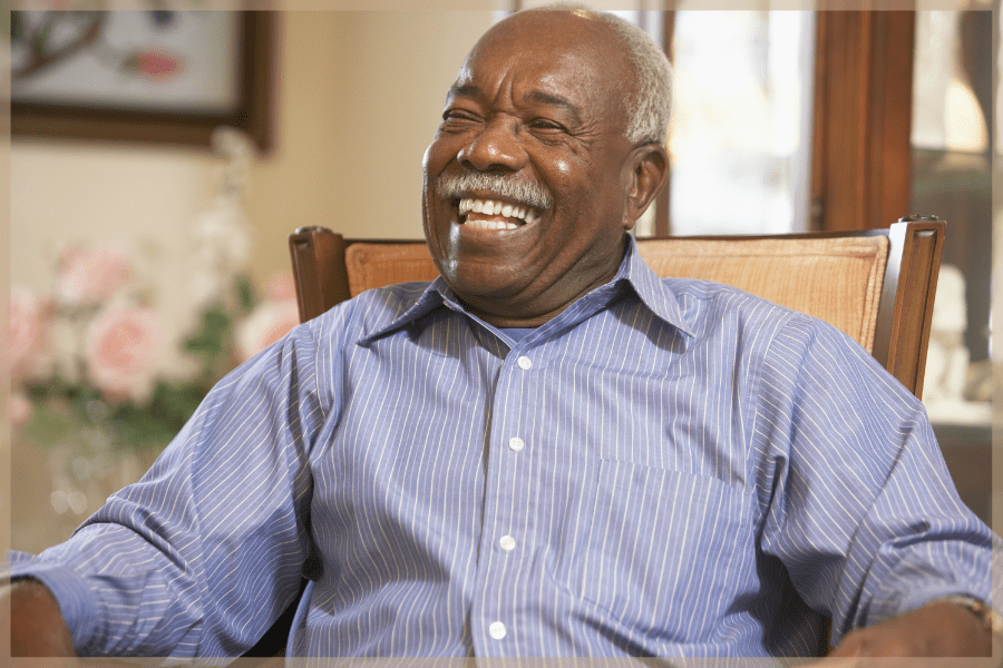 National Dental Hygiene Month - Senior man smiling sitting in a living room chair - MeetCaregivers