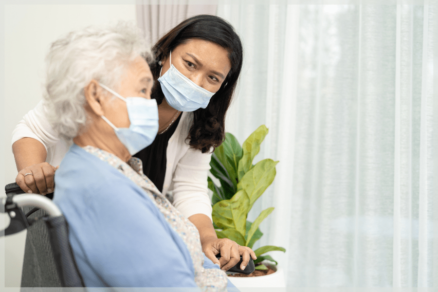 Social isolation in older adults Caregiver checking on elderly patient while pushing her in a wheelchair MeetCaregivers