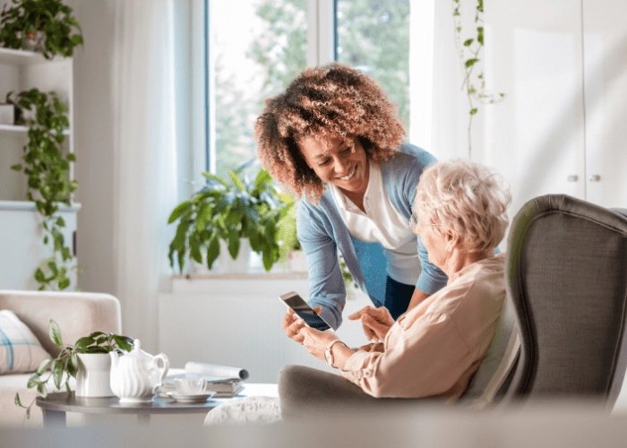 caregiver showing elderly woman how to use a smartphone