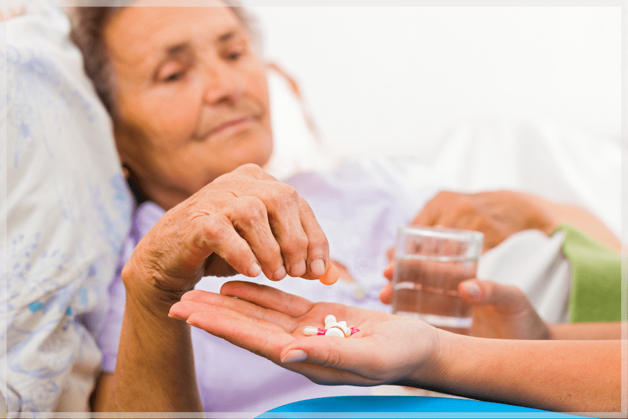 Elderly woman taking medication from a health providers hand MeetCaregivers