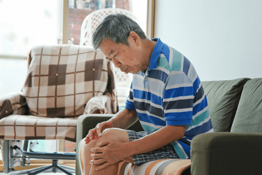 Elderly Man Applying A Bandage To His Sore Knee