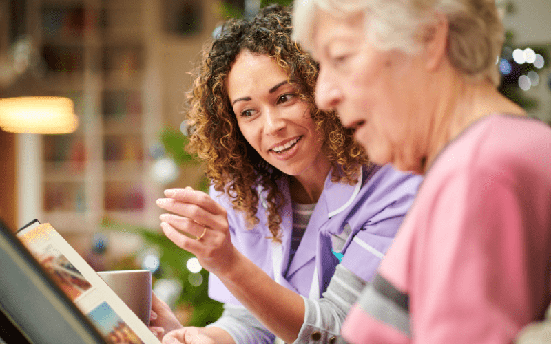 dementia-wandering-in-home-caregiver-looking-at-photo-album-with-elderly-female-patient