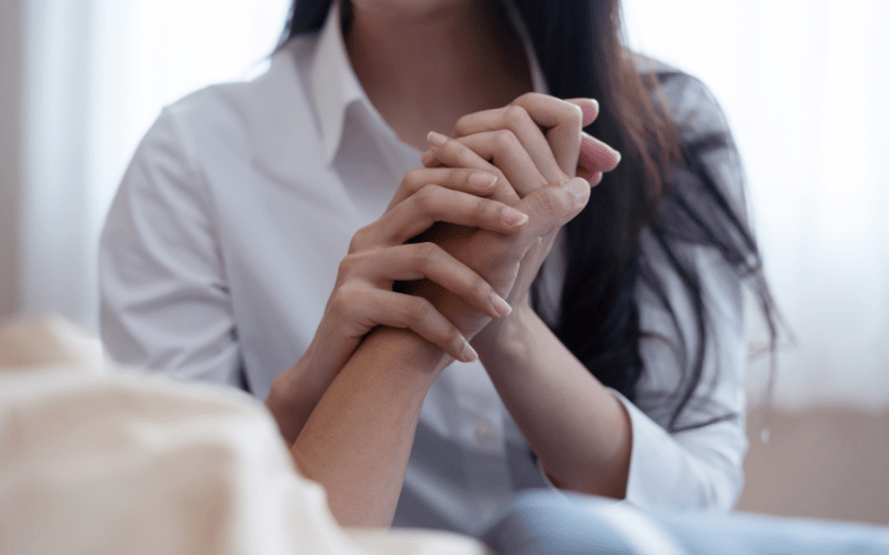 young woman holding loved ones hand