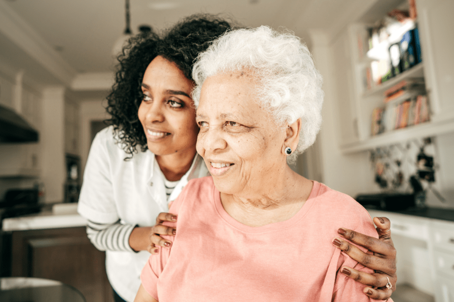 In home caregiver embracing elderly woman