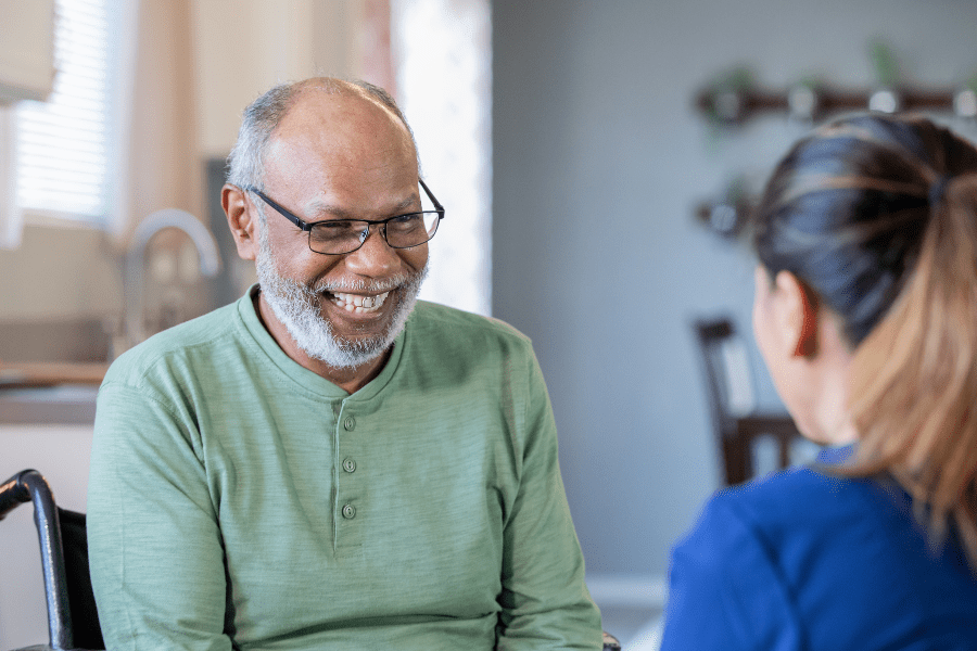 Woman Speaking To Smiling Older Man After Getting Home Health Aide Certification