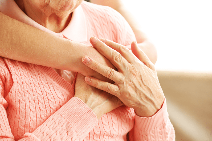 Elderly woman clasping younger person's hands while discussing end-of-life planning