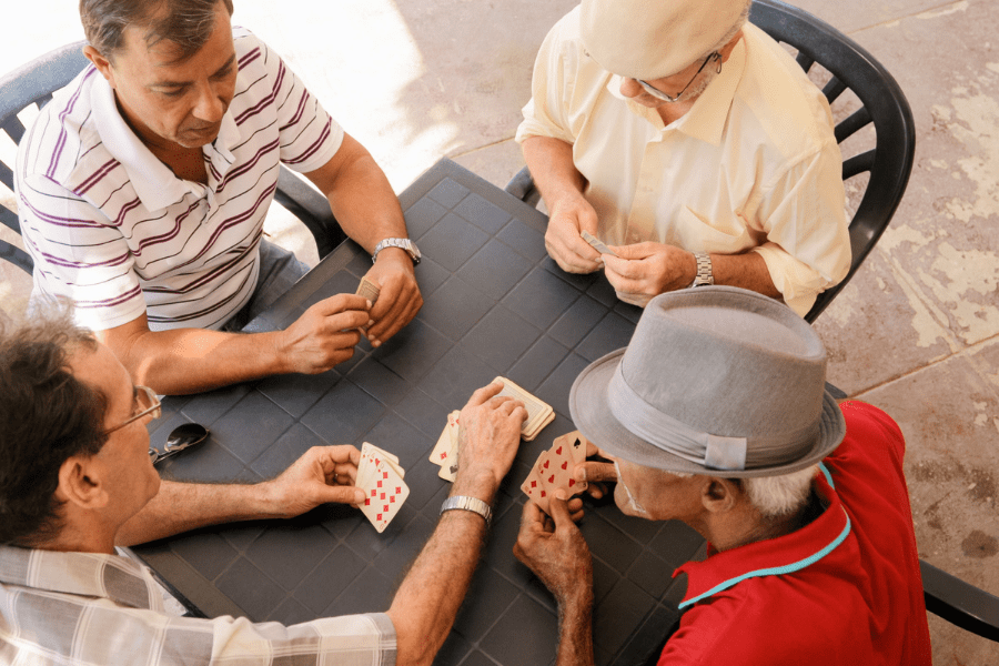 Group Of Senior Men Playing Cards On The Patio