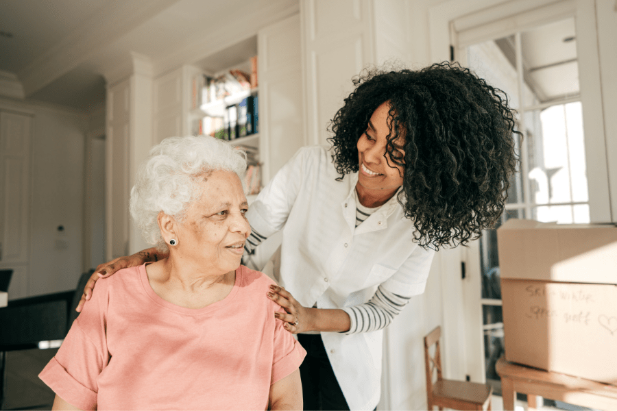 HHA affectionately placing her hands on an elderly clients shoulders.