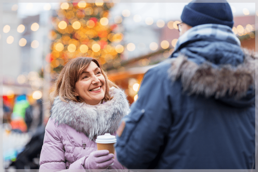 Holiday Stress - Smiling Woman Holding a Cup of Coffee While Chatting to a Man Outdoors - MeetCaregivers