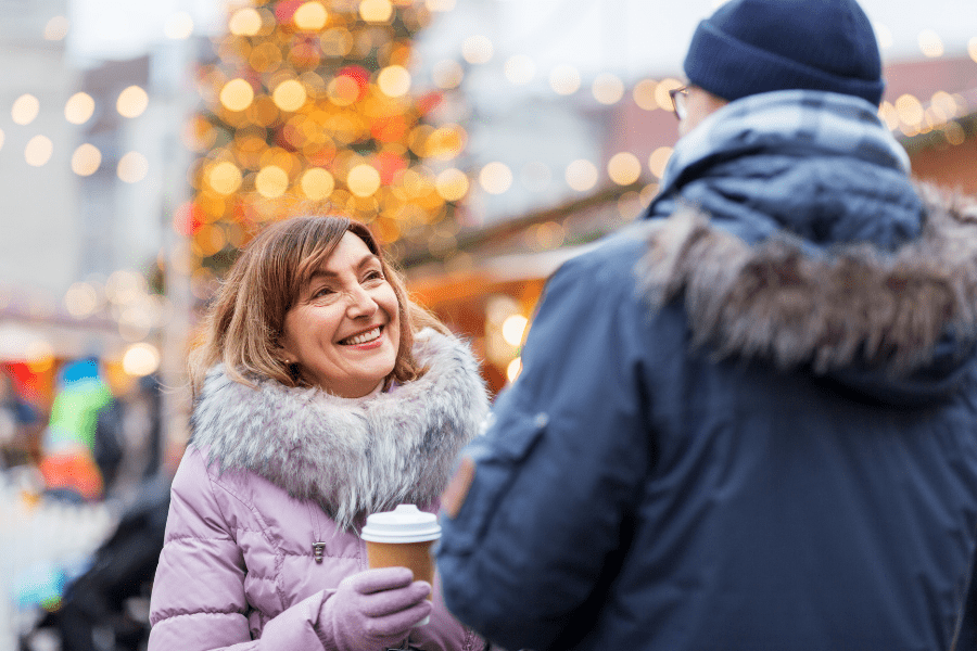 Smiling woman reducing holiday stress by chatting with man outdoors.