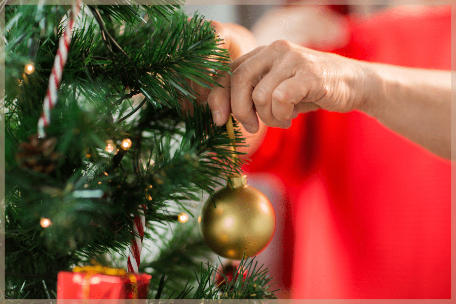 Holiday Stress - Person hanging ornaments on a Christmas tree - MeetCaregivers