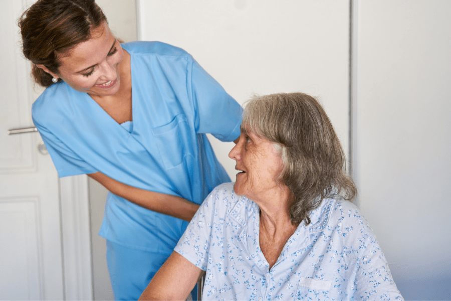 Caregiver Careers – Cheerful nurse assisting a smiling wheelchair bound patient.