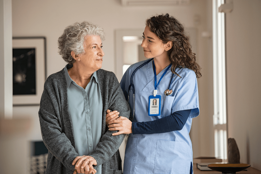 Certified Caregiver Assisting Elderly Woman In A Nursing Home