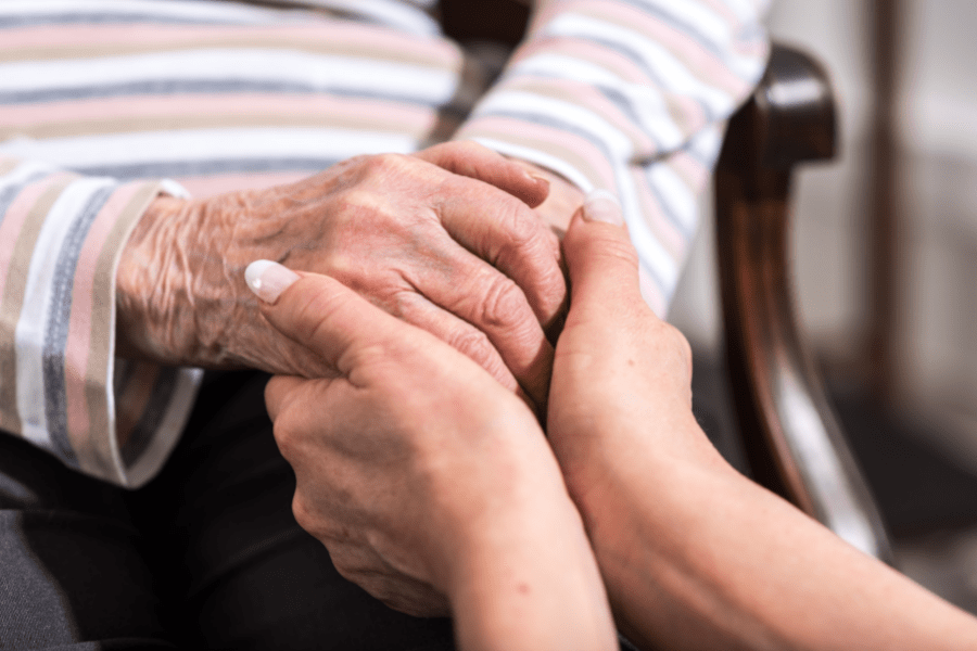 Hands Of A Young Woman Holding The Hands Of An Elderly Woman