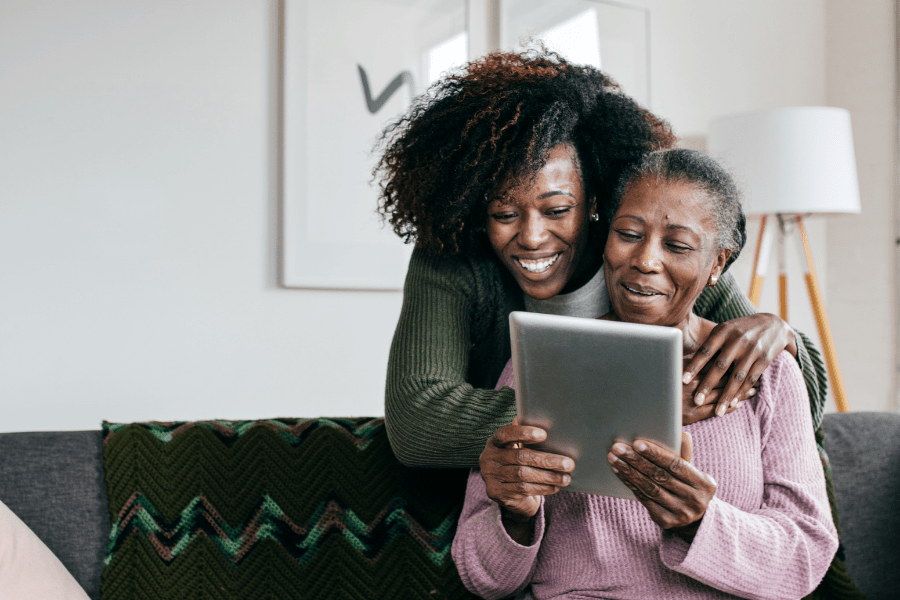 Caregiver and senior woman searching for government assistance for family caregivers on an iPad.