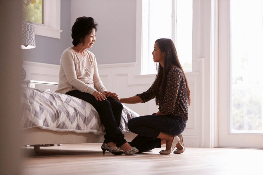 Adult daughter talking to depressed mother at home