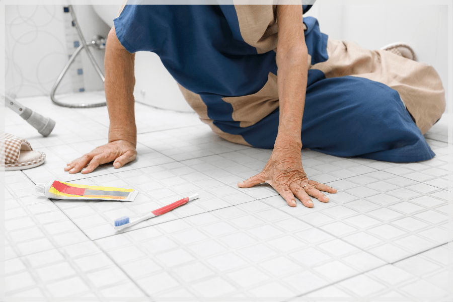 Balance and falling in the elderly - senior woman pushing herself off the ground after falling in the bathroom - MeetCaregivers