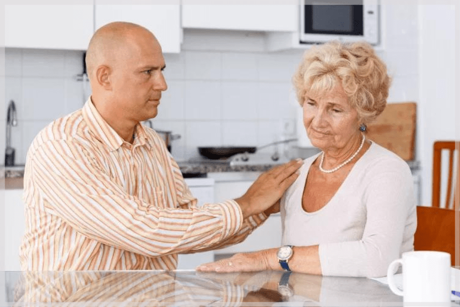 Caring for aging parents – Adult son comforting his elderly mother – MeetCaregivers