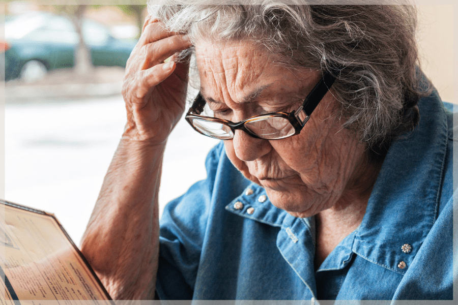 Elder abuse - Elder woman reading a menu with difficulty - MeetCaregivers