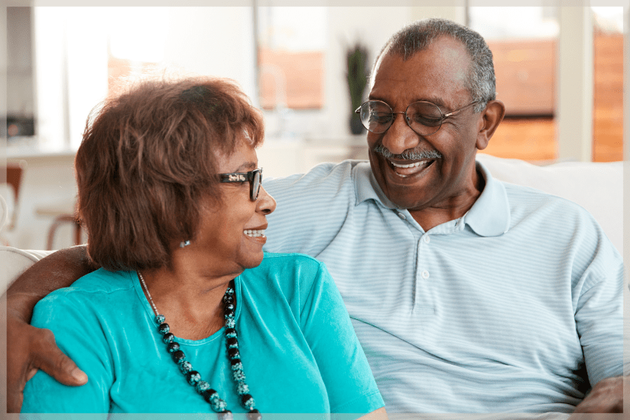 OEP - Senior couple sitting on the couch smiling at each other - MeetCaregivers